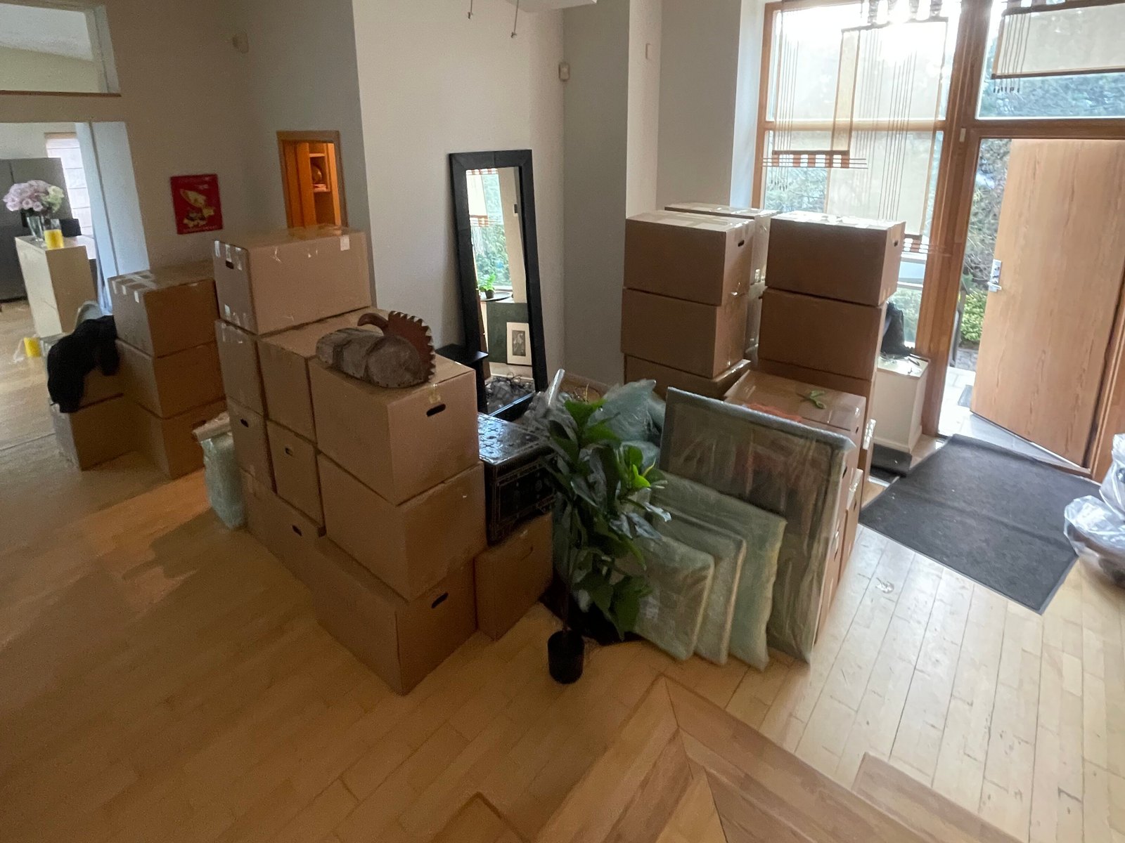Packed moving boxes stacked along a bright house hallway, ready to load
